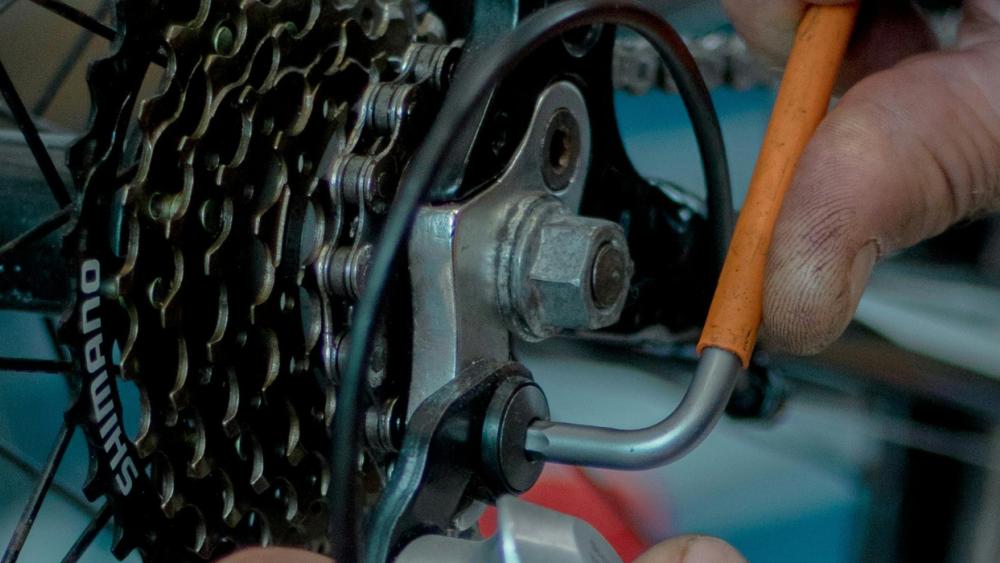 A person performs maintenance on their bicycle by adjusting gears. 